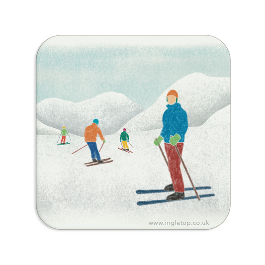 A square coaster with rounded corners, printed with an illustration of skiers in a snowy landscape, on a plain white background