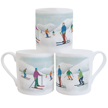 White fine bone china mugs with an illustration of colourful skiers in front of snow-covered mountains, stacked against a white background
